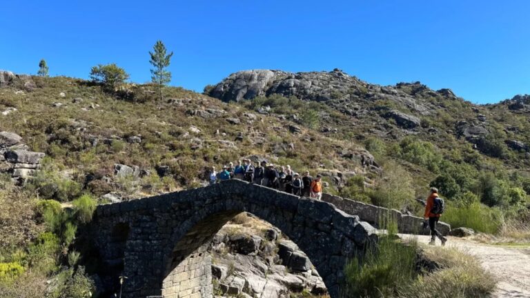 Hiker crossing an old stone bridge in Castro Laboreiro, Peneda-Gerês