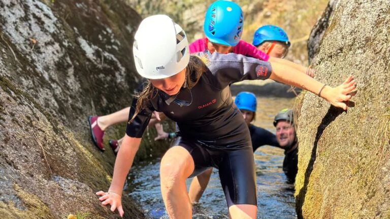River trekking group climbing over granite rocks in Gerês